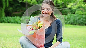 Cheerful young woman smelling flowers