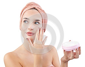 Cheerful young woman smiling, applying on face moisturizing skincare cream, lotion or mask for skin lifting and anti-aging, wears