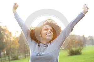 Cheerful young woman smiling with arms raised