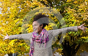 Cheerful young woman standing outdoors with arms outstretched