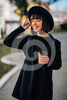 Cheerful young woman in the street drinking morning coffee in sunshine light