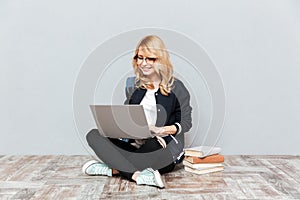Cheerful young woman student using laptop computer.