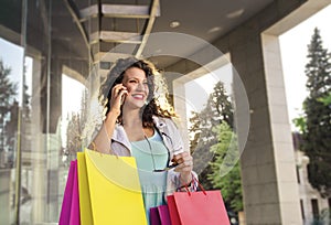Cheerful young woman shopping and holding colorful bags