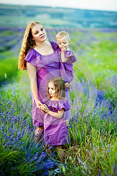 Cheerful young woman with two young girls on the background of beautiful nature in spring