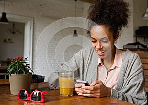 Cheerful young woman typing a text message on mobile phone