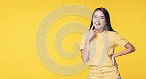Cheerful young woman use finger pointing to her head looking at product or empty copy space while standing over isolated on yellow