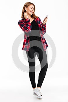 Cheerful young woman using mobile phone listening music