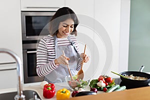 Cheerful young woman vegan making vegetable salad