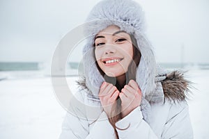 Cheerful young woman wearing hat at cold winter day.