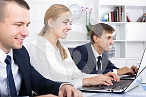 cheerful young woman working with coworkers in office