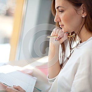 Cheerful young woman writing and keeping her personal a daily diary books.