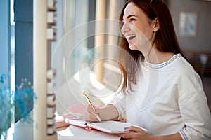 Cheerful young woman writing and keeping her personal a daily diary books.