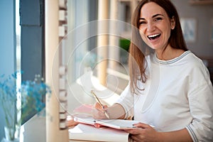 Cheerful young woman writing and keeping her personal a daily diary books.