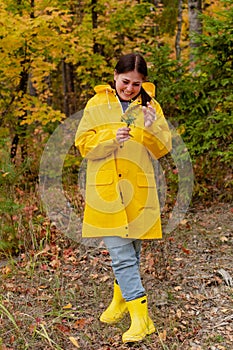 cheerful young woman in a yellow raincoat and yellow boots poses for the camera.