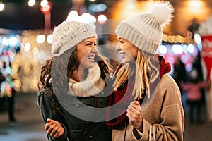 Cheerful young women friends at christmas time are having fun and shopping presents for their family