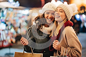 Cheerful young women friends at christmas time are having fun and shopping presents for their family