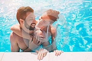 Cheerful youthful guy and lady resting while swimming pool outdoor. Couple in water. Guys do summer sephi