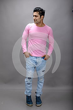 Cheerfull young male model in casual wear wearing pink t-shirt and blue denim jeans. Fitness model. Advertisement shot photo