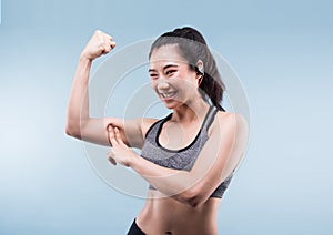 Cheerfully smiling asian sporty woman demonstrating biceps.