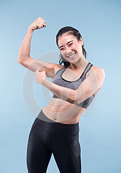 Cheerfully smiling asian sporty woman demonstrating biceps. photo