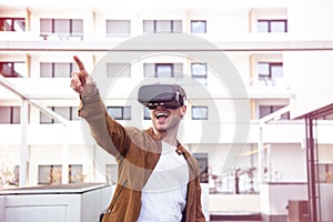 Cheerfully Young Adult Charming Man Using VR Virtual Reality Glasses Outdoor