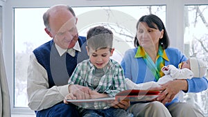 Cheerfulness pensioner family, grandparents with baby learn to read kid