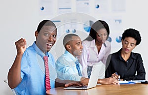 Cheering african american businessman with business team at office