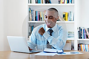 Cheering african american businessman stay at home and working at computer