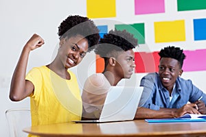 Cheering african american female student at computer with group of students