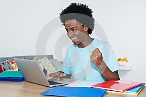 Cheering african american male student with laptop