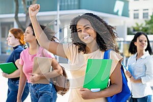 Cheering black female student with group of latin american and caucasian young adults