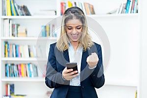 Cheering blond businesswoman receiving good news on phone