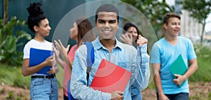 Cheering brazilian male student with braces and group of multi ethnic young adults