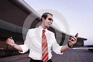 Cheering business man with mobile phone.