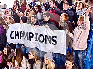 Cheering fans in stadium holding champion banner.
