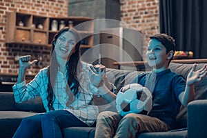 Cheering little boy and his mother watching a soccer game on couch