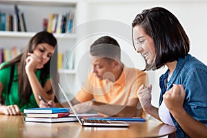 Cheering spanish female student with group of learning students