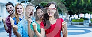 Cheering woman with glasses and young adult friends in line