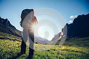 Woman hiker with backpack hiking on high altitude mountain photo