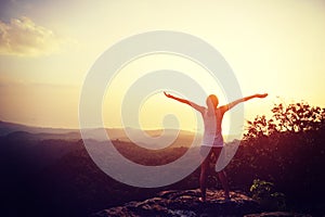 Cheering woman hiker open arms at mountain peak