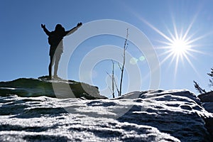Cheering woman hiker open arms at mountain peak backlit with heavy lensflare and ice crystalls in the foreground. photo