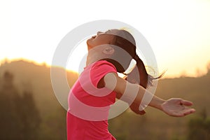 Cheering woman hiker raised arms mountain top