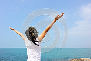 Cheering woman open arms at seaside rock