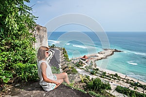 Cheering young caucasian woman on the cliff of mountain. Tropical Bali island, Indonesia, Asia.