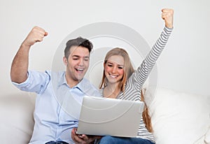 Cheering young couple on a sofa with notebook