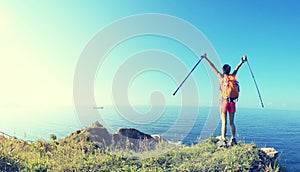 Cheering young woman hiker open arms on seaside mountain