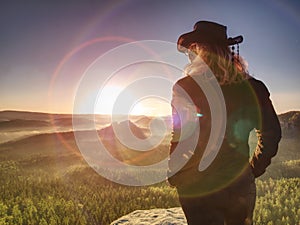 Cheering young woman traveler hiking on rocky promontory