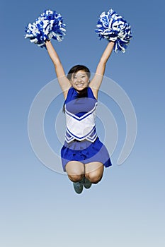 Cheerleader With Pompoms In Midair Against Sky photo