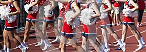 Cheerleaders cheering on the sidelines oduring a high school football game