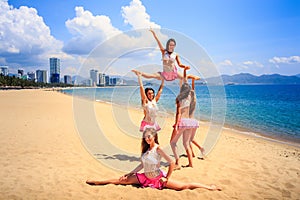 Cheerleaders perform High Straddle Stunt on beach against sea photo